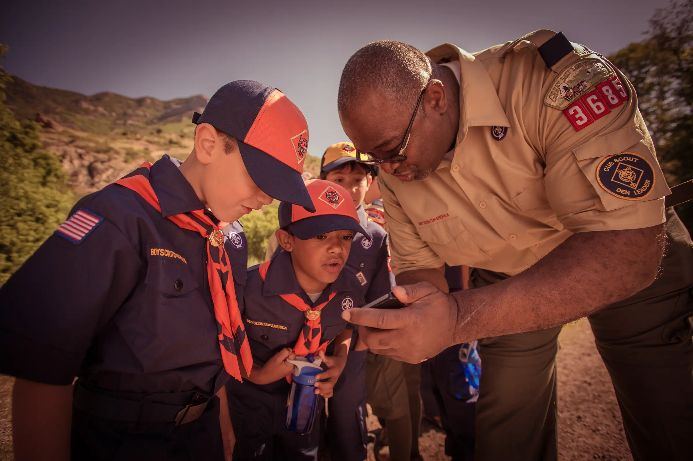 A den leader showing something to two Tiger Scouts